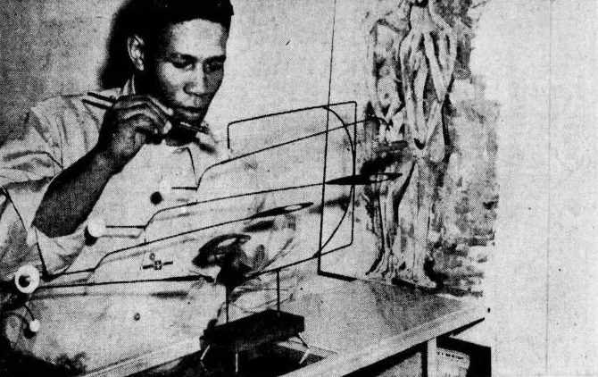 Newspaper photo from 1956: Lieutenant Ronald E. Johnson above a wire mobile, a figurative sculpture behind him