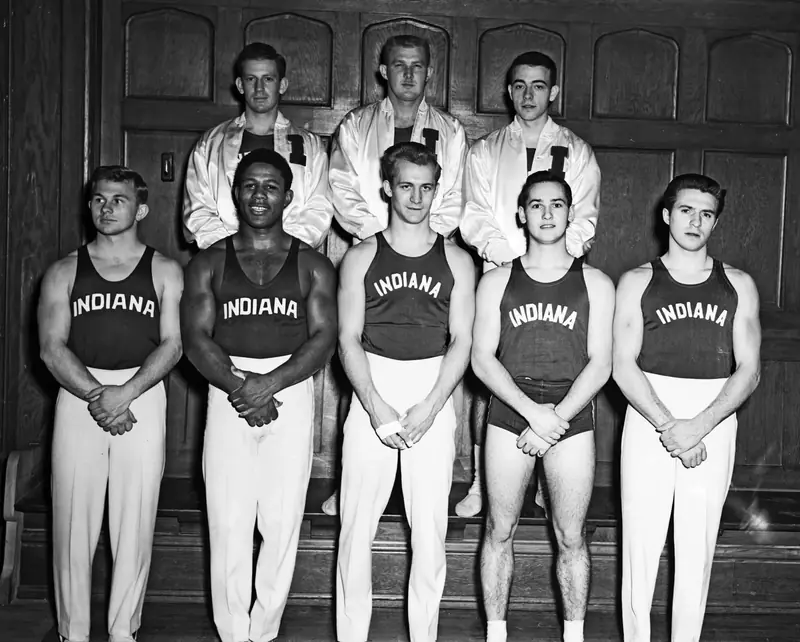 Team photo of the Indiana University gymnastics team, January 1953, the gymnasts in jerseys lettered INDIANA; Johnson in front, second from left