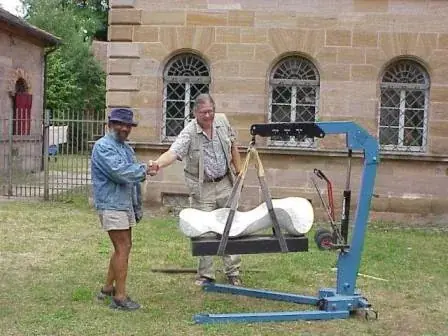 Johnson installing work in the courtyard of Schloss Burgfarrnbach, a white marble sculpture hanging from a crane