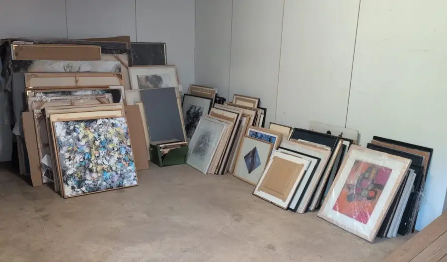 Room with framed and unframed paintings from the estate leaning against the walls