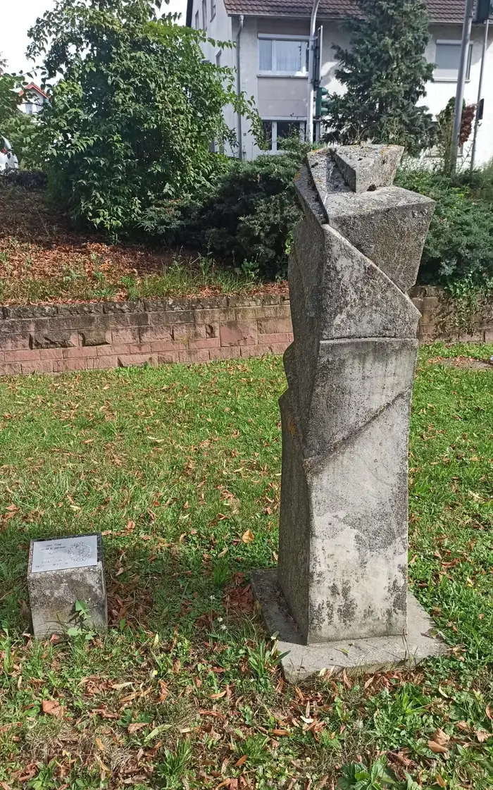 Tall, slender stone sculpture by Johnson on a lawn in the Stadtgraben of Tauberbischofsheim
